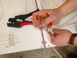 Ein Inhaftierter montiert mit einer Zange Kabel auf Leiterplatten Ein Inhaftierter montiert mit einer Zange Kabel auf Leiterplatten